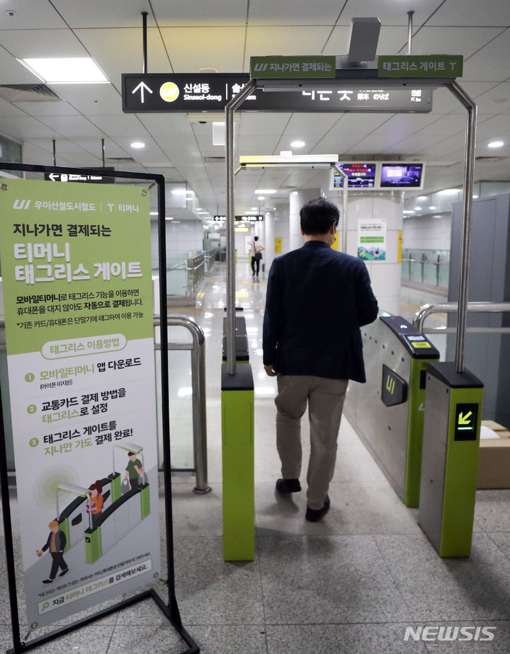 [서울=뉴시스] 최진석 기자 = 6일 서울 강북구 우이신설선 삼양사거리역에 설치된 티머니 태그리스(Tagless) 게이트에서 업체 관계자가 스마트폰 앱 설정 후 교통카드나 스마트폰 태그 없이 개찰구를 통과하고 있다. 서울 지하철 우이신설경전철에서 시행되는 태그리스 결제 서비스는 지하철 게이트에서 블루투스 통신으로 고객의 모바일티머니 정보를 인식하면 자동으로 요금이 차감되는 원리로 안드로이드를 탑재한 스마트폰에 앱을 설치하면 이용 가능하다. 2023.09.06. myjs@newsis.com