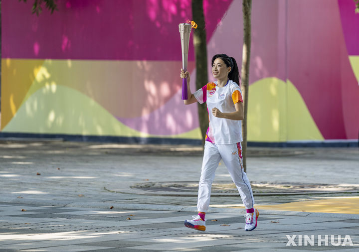[항저우=신화/뉴시스] 뤄쉐쥐안(罗雪娟)이 지난 8일 중국 저장성 항저우에서 열린 제19회 항저우 아시안게임 성화 봉송 첫 주자로서 햇불을 들고 달리고 있다. 2023.09.11.