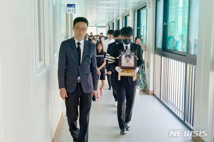 [대전=뉴시스] 유순상 기자=학부모 악성 민원 등에 시달려 극단적인 선택을 한 대전 여교사 운구차량이 9일 근무하던 유성구 한 초등학교에 도착했다. 유족이 영정사진을 들고 생전에 담당했던 교실에서 내려오고 있다. 2023.09.09. ssyoo@newsis.com