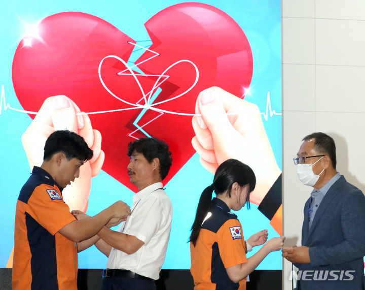 [세종=뉴시스] 강종민 기자 = 지난해 9월15일 세종시 정부세종2청사에서 열린 '119 리본 클럽' 발대식에서 119의 도움으로 심정지 소생자들과 이들을 응급처치 했던 구급대원들이 서로의 가슴에 뱃지를 달아주고 있다. 119리본클럽은 119를 통해 일상을 회복한 심정지 소생자들의 생생한 사례 공유와 확산을 통해 국민에게 심폐소생술의 중요성을 널리 알리고, 심정지환자 소생률을 높이기 위해 구성됐다. 2023.02.22.
