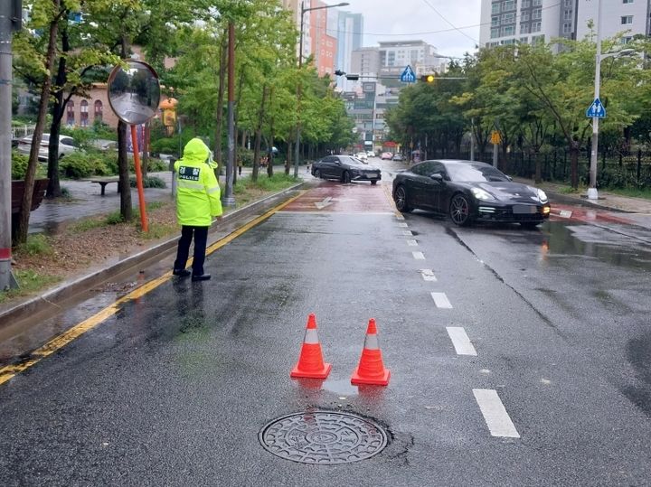 [부산=뉴시스] 호우경보가 발효된 16일 오후 부산 해운대구의 한 도로의 맨홀이 역류해 경찰이 인근 도로를 통제하고 있다. 2023.09.16. (사진=부산소방재난본부 제공) *재판매 및 DB 금지