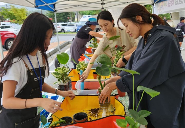 [괴산=뉴시스] 강신욱 기자 = 16일 오후 충북 괴산군 괴산읍 검승리 괴강관광지 불빛공원 광장에서 열린 괴강 불빛·핫·MZ 페스티벌에서 참가자들이 페트병을 활용한 업사이클링 탄소 정화식물 심기 체험을 하고 있다. (사진=중원청소년문화복지센터 제공) 2023.09.16. photo@newsis.com *재판매 및 DB 금지