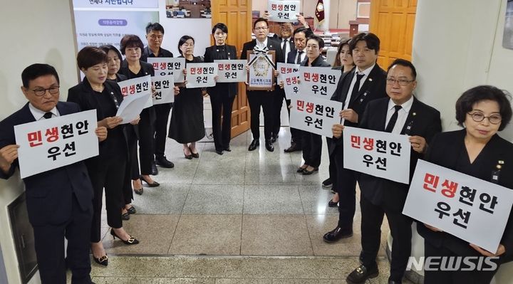 경기 고양시의회 국민의힘 소속 의원들이 21일 본회의장 앞에서 더불어민주당 의원들을 향해 소모적인 정쟁 중단을 촉구하고 있다.