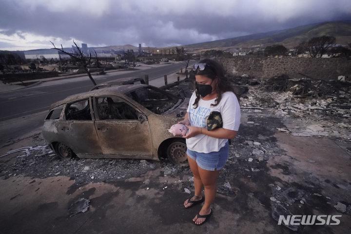 [서울=AP/뉴시스] 미국 하와이주 라하이나에서 산불이 발생한 지 한 달여 만에 일부 주민들이 터전으로 돌아갈 수 있게 됐다고 25일(현지시간) 미국 CNN, 하와이안뉴스나우 등 외신이 보도했다. 사진은 지난 8월10일 미국 하와이주 라하이나에서 발생한 산불 이후 집 잔해에서 발견한 돼지 저금통을 줍고 있는 주민의 모습. 2023.09.26.