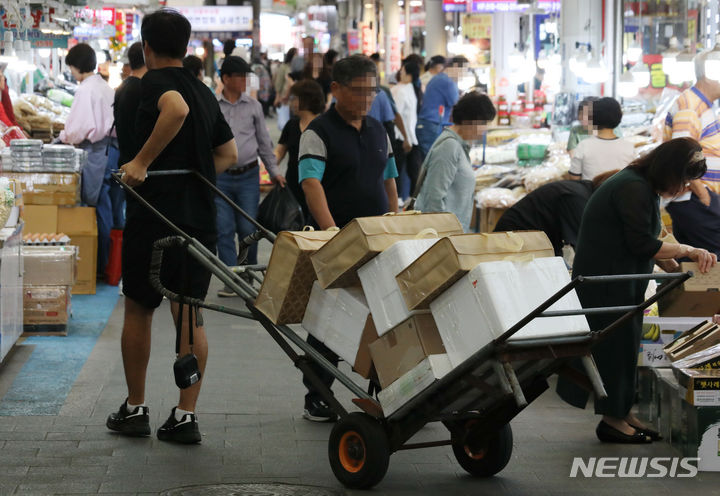 [서울=뉴시스] 최진석 기자 = 22일 서울 한 전통시장에서 상인이 추석 제수용품 선물세트 손수레로 옮기는 모습. 2023.09.22. myjs@newsis.com