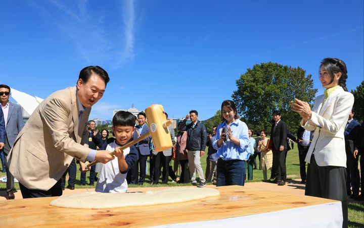 [서울=뉴시스] 윤석열 대통령이 추석을 앞둔 24일 서울 용산어린이정원에서 운영 중인 팔도장터를 방문해 어린이와 함께 떡메치기 체험을 하고 있다. (사진=대통령실 제공) 2023.09.24. photo@newsis.com *재판매 및 DB 금지