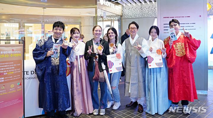 [서울=뉴시스]사진은 지난 26일 롯데면세점 명동본점 앞에서 김주남 롯데면세점 대표이사(오른쪽 세 번째)와 임직원들이 추석을 맞이해 K컬처 문화 체험부스 이벤트를 열고 외국인 고객들을 맞이하고 있다.2023.09.27.(사진=롯데면세점 제공)photo@newsis.com