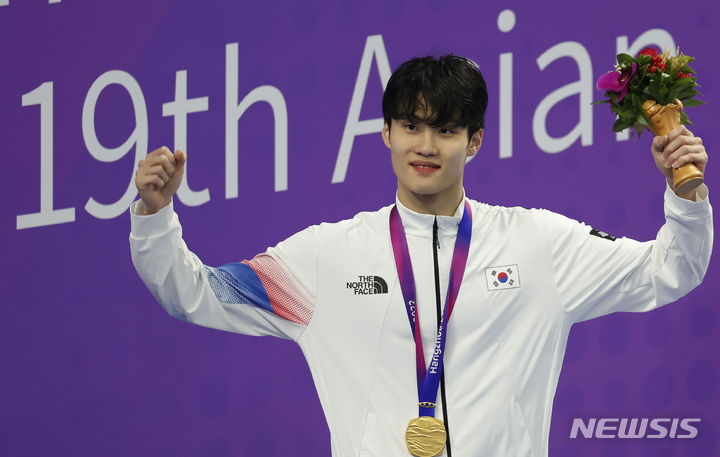 [항저우=뉴시스] 정병혁 기자 = 2022 항저우 아시안게임 남자 자유형 200m에서 금메달을 차지한 황선우가 27일 중국 항저우 올림픽 스포츠센터 수영장에서 열린 시상식에서 메달을 목에 걸고 손을 흔들고 있다. 2023.09.27. jhope@newsis.com