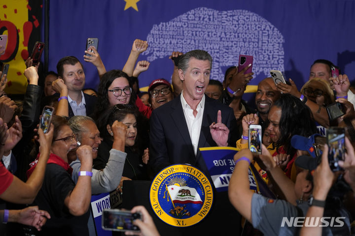 [로스앤젤레스=AP/뉴시스] 미국 캘리포니아주가 오는 4월부터 최저시급을 전국 최고 수준인 20달러로 인상할 계획을 본격화하며 프랜차이즈 업체들이 대규모 해고로 임금 상승에 대응하는 등 혼란이 빚어지고 있다. 사진은 지난해 9월 개빈 뉴섬 캘리포니아 주지사가 지지자들에 둘러싸인 채 임금 인상 법안에 서명하는 모습. 2024.01.18.