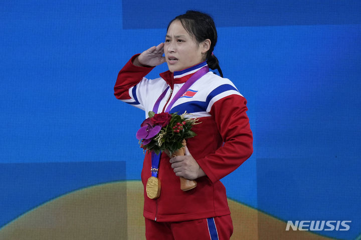 [항저우=AP/뉴시스] 북한 리성금이 30일 중국 항저우 샤오산 스포츠 센터 체육관에서 열린 2022 항저우 아시안게임 여자 49kg급 시상식에서 금메달을 목에 걸고 거수경례하고 있다. 리성금은 이날 인상 92kg, 용상 124kg, 합계 216kg을 들어 장후이화가 가진 합계 세계 기록(215kg)보다 1kg을 더 들어 올리며 우승을 차지했다. 2023.09.30.