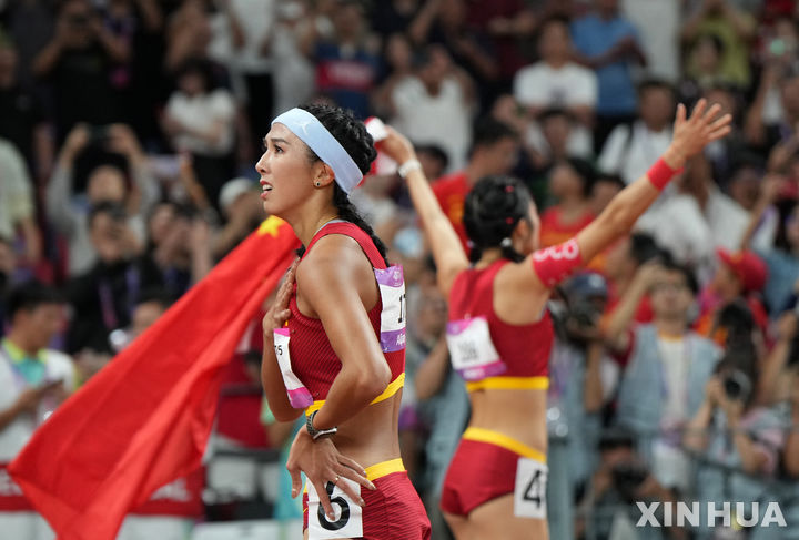 [항저우=신화/뉴시스] 1989년 6월4일 톈안먼 민주화 시위(톈안먼 사태)를 연상시키는 장면이 2022 항저우 아시안게임에서 우연히 연출돼 중국 관영 매체가 관련 사진을 삭제하는 일이 일어났다. 사진은 지난 1일 항저우 아시안게임 여자 육상 100m 허들 결승전 직후 금메달을 딴 중국 선수 린위웨이(왼쪽)와 우옌니가 관중에 인사하는 모습. 2023.10.05.