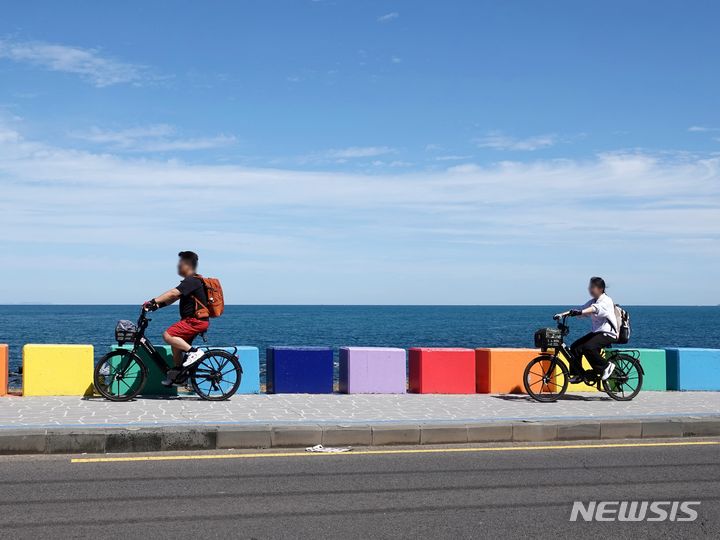 [제주=뉴시스] 오영재 기자 = 선선한 날씨를 보이는 2일 오전 제주 도두동무지개해안도로에서 관광객들이 전동 자전거를 타고 있다. 2023.10.02. oyj4343@newsis.com