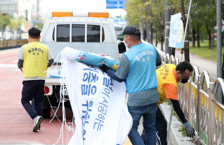 [광주=뉴시스] 변재훈 기자 = 광주 북구청 광고물관리팀 직원들이 11일 북구 신용동 일대에서 무분별하게 걸려있는 아파트 분양 광고 불법 현수막을 수거하고 있다. (사진 = 광주 북구 제공) 2023.10.11. photo@newsis.com *재판매 및 DB 금지