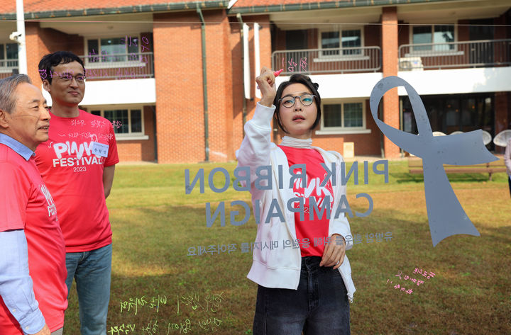 [서울=뉴시스] 윤석열 대통령 부인 김건희 여사가 15일 서울 용산구 용산공원 장교숙소에서 열린 2023 핑크 페스티벌에 참석해 핑크리본 캠페인 메시지를 작성하고 있다. (사진=대통령실 제공) 2023.10.15. photo@newsis.com *재판매 및 DB 금지