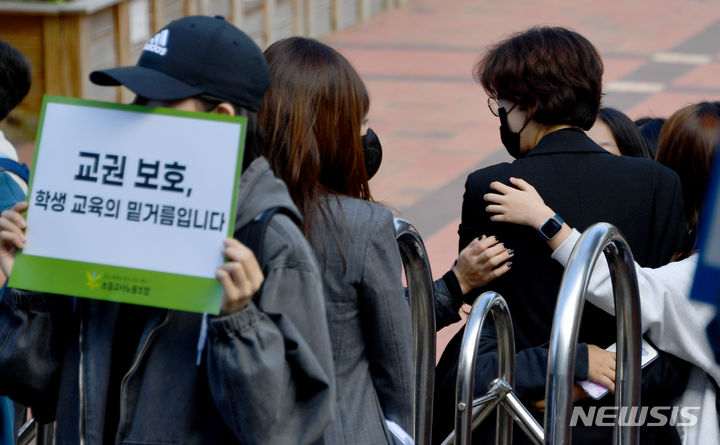 [광주=뉴시스] 류형근 기자 = 초등교사노동조합이 24일 오후 광주 북구 한 초등학교 앞에서 "1년여의 재판끝에 아동학대 무혐의 판결된 교사에 대한 교권회복"을 촉구하고 있는 가운데 학생들이 하교 중에 교사를 위로하고 있다. 2023.10.24. hgryu77@newsis.com