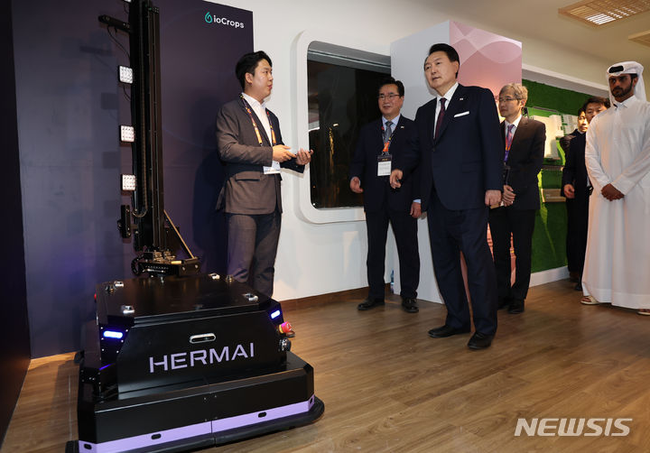 [도하=뉴시스] 전신 기자 = 카타르를 국빈 방문한 윤석열 대통령이 지난해 10월24일(현지시간) 도하 알 비다 공원에서 열린 국제원예박람회 한국관 개관식에 참석, 한국형 스마트 농업 전시관을 찾아 조진형(왼쪽) 아이오크롭스 대표로부터 생육 모니터링 자율주행 작물관찰로봇 헤르마이에 대한 설명을 듣고 있다. 2023.10.25. photo1006@newsis.com