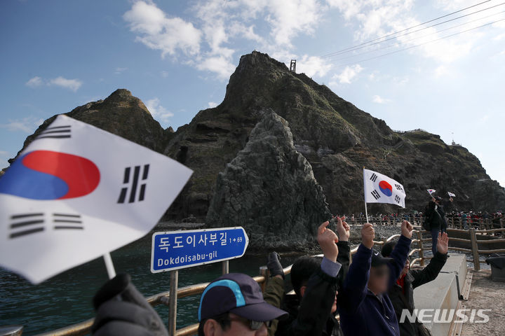 [독도=뉴시스] 조성우 기자 = 지난 2021년 10월 31일 경북 울릉군 독도 선착장에서 관광객들이 태극기를 들고 기념촬영을 하고 있다. 2023.10.25. xconfind@newsis.com