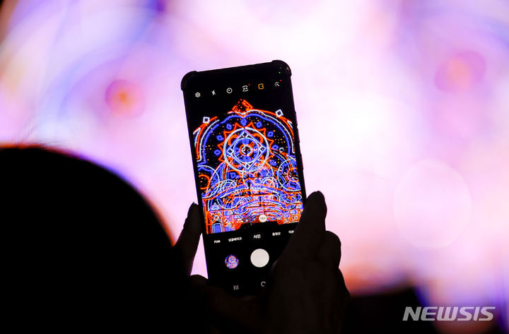 [서울=뉴시스] 정병혁 기자 = 27일 서울 송파구 석촌호수에서 열린 '호수의 가을과 겨울 그리고 루미나리에'를 찾은 시민들이 형형색색으로 꾸며진 빛 터널을 지나며 사진을 찍고 있다. 2023.10.27. jhope@newsis.com