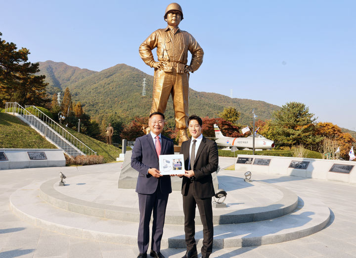 백선엽 장군 동상 앞에서 최영재(오른쪽)씨가 군번줄로 만든 액자를 김재욱 군수에게 전달하고 있다 (사진=칠곡군 제공) *재판매 및 DB 금지