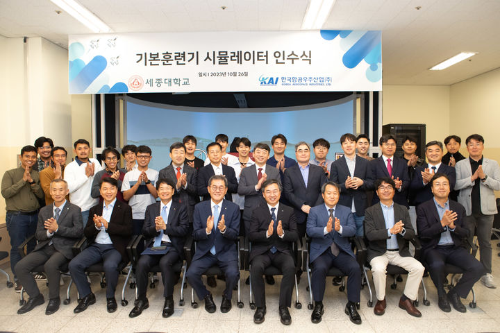 배덕효 세종대 총장(앞줄 왼쪽에서 4번째)과 한국항공 미래사업부문장 상무(왼쪽 5번째)가 KT-1 시뮬레이터 앞에서 기념사진을 촬영하고 있다. (사진=세종대 제공) *재판매 및 DB 금지