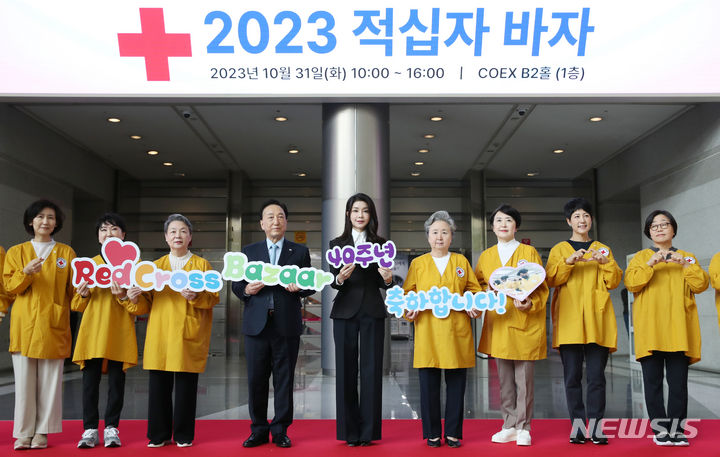 [서울=뉴시스] 전신 기자 = 윤석열 대통령 부인 김건희 여사가 31일 서울 강남구 코엑스에서 열린 2023 적십자 바자 행사에서 참석자들과 함께 적십자 바자 40회를 기념하는 판넬을 들고 기념촬영하고 있다. 2023.10.31. photo1006@newsis.com