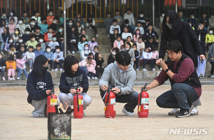 [수원=뉴시스] 김종택기자 = 31일 경기도 수원시 영화초등학교에서 열린 '2023 재난대응 안전한국훈련'에서 학교 관계자와 학생들이 소화기 작동법을 배우고 있다. 2023.10.31. jtk@newsis.com