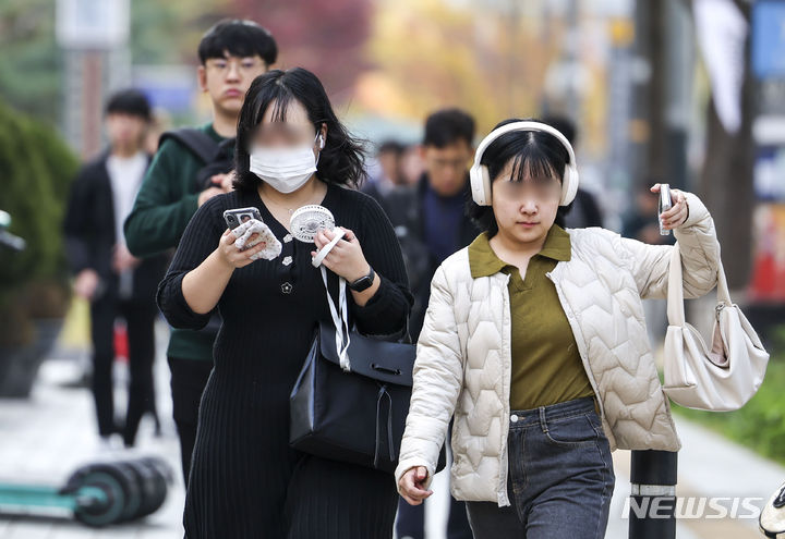 [서울=뉴시스] 정병혁 기자 = 낮 최고기온이 21~28도로 예보된 2일 서울 종로구 세종대로 인근에서 한 시민이 손선풍기를 들고 이동하고 있다.  2023.11.02. jhope@newsis.com