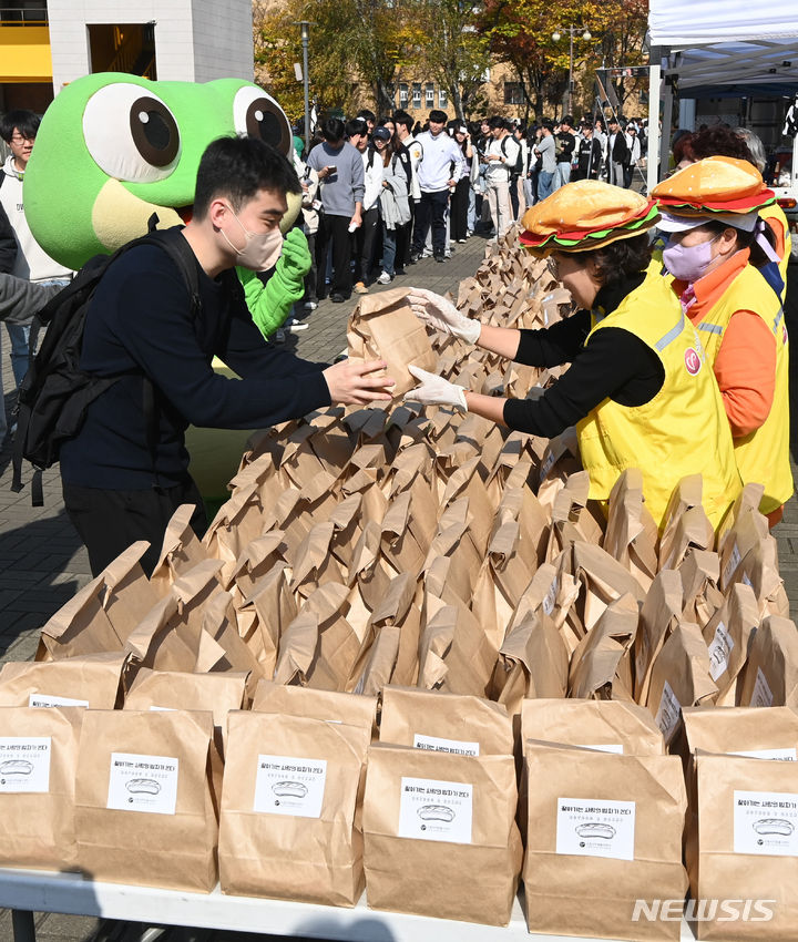 [수원=뉴시스] 김종택기자 = '찾아가는 사랑의 밥차' 행사가 열린 2일 경기도 수원시 성균관대학교 자연캠퍼스에서 수원자원봉사센터 관계자들이 학생들에게 핫도그를 나눠주고 있다. 2023.11.02. jtk@newsis.com