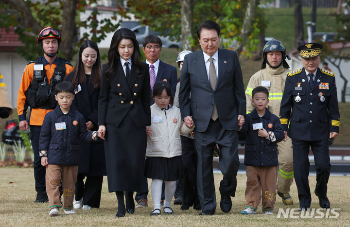 [서울=뉴시스] 전신 기자 = 윤석열 대통령과 부인 김건희 여사가 9일 서울 용산어린이정원 잔디마당에서 열린 제61주년 소방의 날 기념식에 순직 소방관 자녀들과 손을 잡고 함께 입장하고 있다. 2023.11.09. photo1006@newsis.com