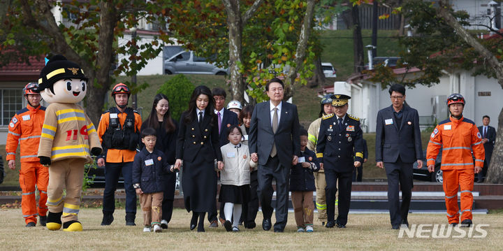 [서울=뉴시스] 전신 기자 = 윤석열 대통령과 부인 김건희 여사가 9일 서울 용산어린이정원 잔디마당에서 열린 제61주년 소방의 날 기념식에 순직 소방관 자녀들과 손을 잡고 함께 입장하고 있다. 2023.11.09. photo1006@newsis.com
