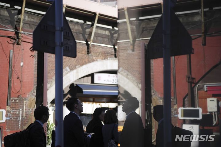 [도쿄=AP/뉴시스]지난해 11월13일 도쿄 신바시 상업지구의 한 건물 유리벽에 보행자가 비쳐지고 있다. 2024.02.26.