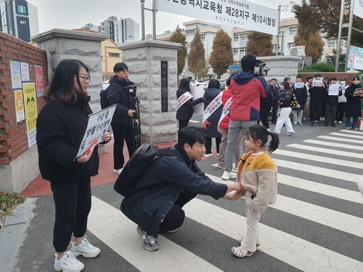 [울산=뉴시스] 구미현 기자 = 수능일인 16일 울산 학성여고 정문 앞에서 6살 난 여자아이가 수험생을 응원하고 있다. 2023.11.16. gorgeouskoo@newsis.com *재판매 및 DB 금지