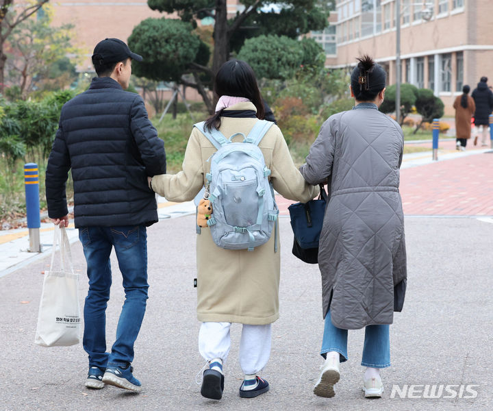 [인천=뉴시스] 전진환 기자 = 2024학년도 대학수학능력시험일인 16일 인천 미추홀구 인화여자고등학교에 마련된 시험장에 한 수험생이 부모님과 손을 잡고 도착하고 있다 2023.11.16. amin2@newsis.com