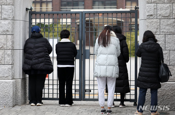 [서울=뉴시스] 홍효식 기자 = 2024학년도 대학수학능력시험날인 16일 서울 강남구 휘문고등학교 교문 앞에서 학부모들이 자녀들의 수능 선전을 기원하며 학교를 바라보고 있다. 2023.11.16. yesphoto@newsis.cm