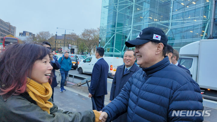 [런던=뉴시스] 전신 기자 = 영국을 국빈 방문 중인 윤석열 대통령이 21일(현지시간) 런던 시내를 산책하던 중 지나가던 시민(일본인)이 다가와 악수를 청하자 악수하고 있다. 윤 대통령이 쓴 모자는 산책시 항상 착용하는 천안함 모자. (사진=대통령실 제공) 2023.11.21. photo1006@newsis.com