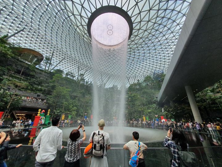 [싱가포르=뉴시스] 홍찬선 기자 = 23일 오전 싱가포르 창이공항에서 승객들이 떨어지는 폭포수를 보며 환호하고 있다. 2023.11.23. mania@newsis.com *재판매 및 DB 금지