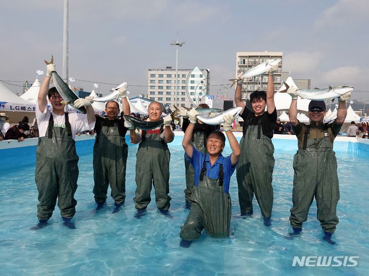 [제주=뉴시스] 오영재 기자 = 23일 오전 제주 서귀포시 모슬포항 일원에서 열린 제23회 최남단 방어축제에서 맨손 방어 잡기 체험에 참여한 시민이 방어를 들고 있다. 2023.11.23. oyj4343@newsis.com