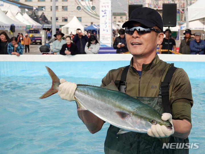 [제주=뉴시스] 오영재 기자 = 23일 오전 제주 서귀포시 모슬포항 일원에서 열린 제23회 최남단 방어축제에서 방어 맨손 잡기 체험에 참여한 시민들이 방어를 들고 있다. 2023.11.23. oyj4343@newsis.com