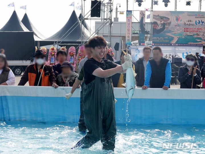 [제주=뉴시스] 오영재 기자 = 23일 오전 제주 서귀포시 모슬포항 일원에서 열린 제23회 최남단 방어축제에서 방어 맨손 잡기 체험에 참여한 시민이 방어를 들어 보이고 있다. 2023.11.23. oyj4343@newsis.com