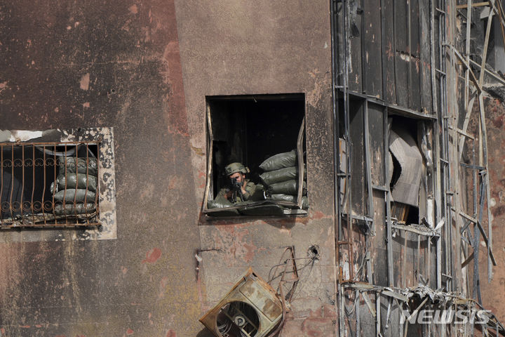 [가자지구=AP/뉴시스] 이스라엘방위군(IDF)은 28일(현지시간) 팔레스타인 무장 정파 하마스가 12명의 인질을 추가 석방 했다고 밝혔다. 사진은 지난 26일 가자지구 살라 알딘 도로변 한 건물에서 이스라엘 군인이 남쪽으로 대피하는 팔레스타인 주민들을 지켜보고 있는 모습. 2023.11.29.