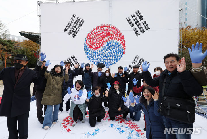 [서울=뉴시스] 고승민 기자 = 26일 서울 보신각 앞 광장에서 국학원 주최로 열린 '대한민국 100만 손도장 태극기몹' 캠페인에서 참가자들이 손도장으로 태극기에 색을 입힌 뒤 기념촬영하고 있다. 2023.11.26. kkssmm99@newsis.com