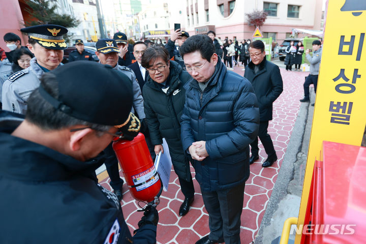  문정중학교 후문에 설치된 안심 비상벨과 비상소화장치를 살펴보고 소화기 사용법에 대한 설명을 듣는 이상일 시장.