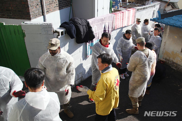 [평택=뉴시스] 차량이 들어 설 수 없는 골목길에 한 줄로 길게 서 연탄을 나르는 모습