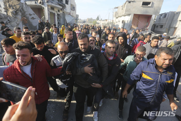 [가자지구=AP/뉴시스] 지난 12월 4일 가자지구 남부 라파에서 한 주민(가운데)이 이스라엘의 폭격으로 숨진 가족의 시신을 안아 옮기고 있다. 이스라엘은 가자지구에서 하루 동안 400곳에 달하는 목표물에 공습을 퍼부었고 가자지구 남부에서의 지상 작전도 본격화했다. 2024.01.01.