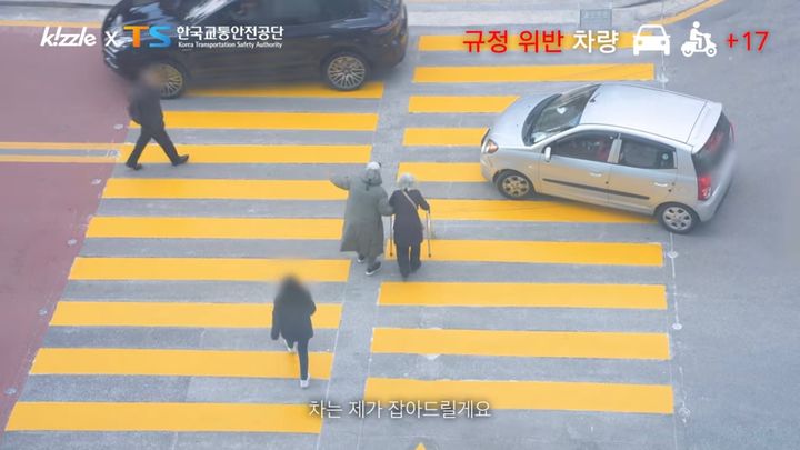 두 대의 차량이 일시 정지 규정을 위반하는 중 중년 남성이 어르신이 안전하게 횡단보도를 건널 수 있도록 도와드리고 있다. (사진=유튜브 채널 키즐 kizzle 캡처) *재판매 및 DB 금지