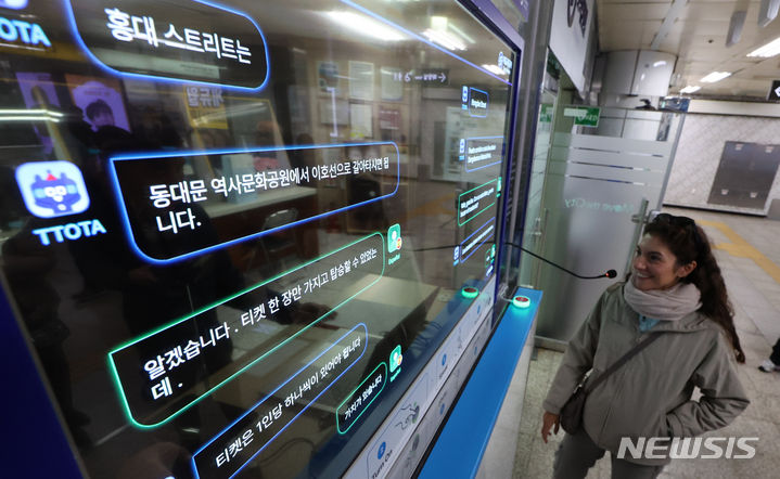 [서울=뉴시스] 황준선 기자 = 4일 오후 서울 지하철 4호선 명동역에서 외국인 관광객이 외국어 동시 대화 시스템을 이용하고 있다. 이날부터 명동역에서 시범 운영에 들어간 외국어 동시 대화 시스템은 투명 OLED 디스플레이를 통해 외국인과 직원이 자국의 언어로 동시에 대화할 수 있으며 13개 언어를 지원한다. 2023.12.04. hwang@newsis.com