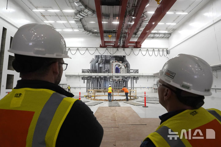 [데벤스=AP/뉴시스] 2023년 10월11일 미국 매사추세츠주 데벤스의 커먼웰스 퓨전 시스템즈에서 근로자들이 실제 크기의 핵융합 장치 모형 앞에 서 있다. 2025.05.20.