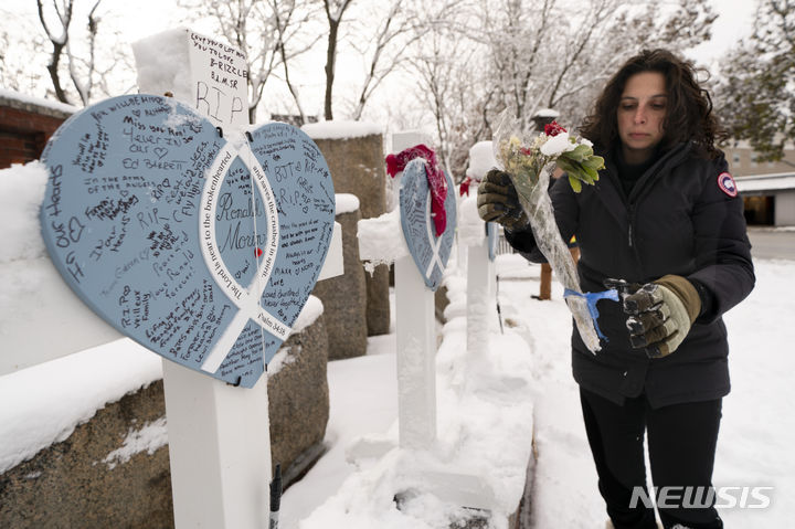 [루이스턴 ( 미 메인주)=AP/뉴시스] 볼링장 총기 난사로 핼러윈 전날인 10월 25일 18명이 죽고 13명이 다친 미국 메인주의 루이스턴에서 거리에 높인 희생자에 대한 추모글과 꽃다발 등 기념물들을 박물관에 수장, 영구 보존하기로 했다. 사진은 12월 2일 눈에 덮힌 꽃다발을 살피는 레이첼 페란테 박물관장. 