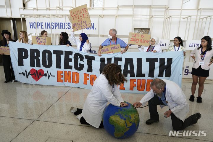 [두바이=AP/뉴시스] 유엔기후변화협약 당사국총회(COP28)가 최종 합의에 이르지 못한 채 12일(현지시간) 폐막하자, 논의는 '연장전'에 들어섰다. 사진은 지난 6일 제28차 COP28가 열리는 아랍에미리트(UAE) 두바이에서 환경 운동가가 지구에 청진기를 대고 심폐소생술로 되살리는 퍼포먼스를 하는 모습. 2023.12.13.