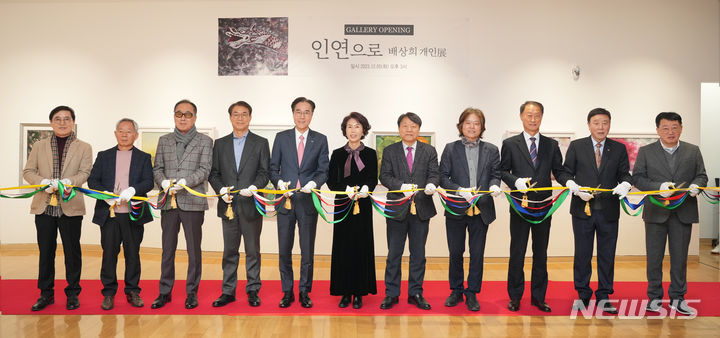 [창원=뉴시스]홍정명 기자=지난 5일 BNK경남은행 창원 본점 BNK경남은행갤러리에서 열린 '인연으로' 주제 배상희 개인전 오픈 행사에 참석한 예경탁(왼쪽 다섯 번째부터) 은행장, 배상희 작가 등이 기념 테이프를 자르고 있다.(사진=BNK경남은행 제공) 2023.12.06. photo@newsis.com